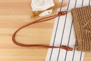 Close-up of woven shoulder bag with khaki texture, leather straps and metal zipper