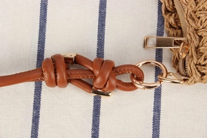 Detail of woven straw bag with premium leather knotted strap and golden metal zipper