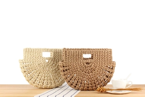 Close-up of woven straw handbags in beige and tan on a wooden table with soft lighting