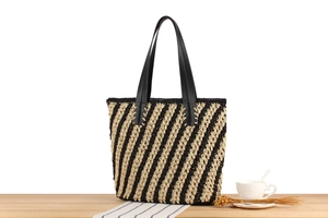 Close-up of the woven texture and black leather handles on a striped beach tote bag