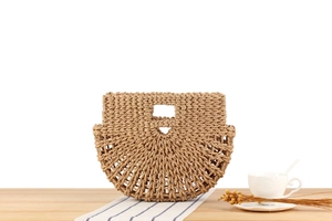 Detailed texture of hand-woven straw tote bag on wooden table with holiday vibes
