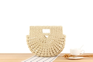 Detail of hand-woven beige straw bag with hollow pattern on rustic wooden table