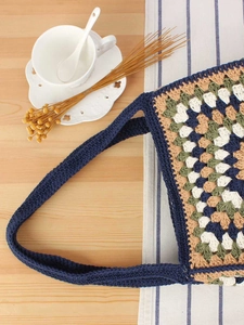 Handmade crochet tote bag with colorful granny square patterns and blue woven straps