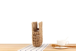 Detailed view of handmade woven straw bag on a wooden table with natural aesthetic