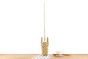 Vue détaillée d'un sac seau en paille tissée avec bandoulière sur table en bois rustique