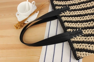Close-up of black and beige striped woven tote bag with leather handles and stitching