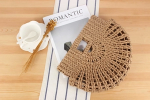 Detail view of woven straw tote bag with intricate patterns on a rustic wooden table