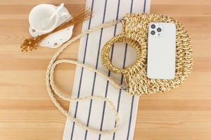 Détail du sac en paille demi-lune avec tissage doré métallisé et poignées rondes