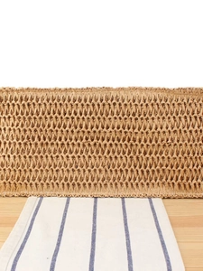 Handwoven straw beach bag with natural texture displayed on a rustic wooden table
