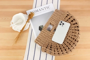 Top view of a semi-circular woven straw handbag with hollow mesh texture on a stylish table