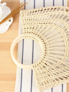 Chic beige woven handbag with hard round handles for elegant summer beach vacations