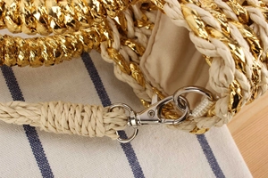 Détail du sac en paille tressée dorée avec fermoir en métal et doublure beige