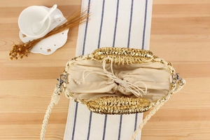 Détail du sac en paille tissée avec accents dorés et fermeture à cordon beige sécurisée