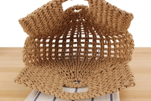 Detail view of woven straw beach bag showing internal mesh structure and round base