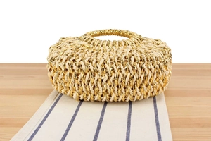 Détail d'un sac rond en paille tissée avec des fibres dorées et naturelles mélangées