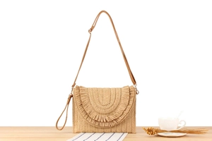 Detail of woven straw crossbody bag featuring layered fringe and a smooth leather strap