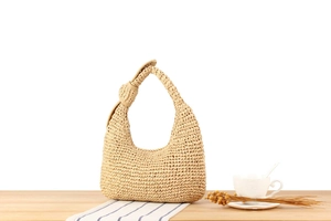 Detail shot of hand-woven hobo bag with unique knot handle design and straw texture