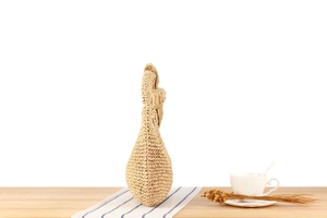 Detail of woven straw handbag on a wooden table with coffee and summer decor