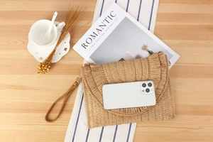 Detail showing natural straw clutch bag capacity with fringe trim and leather wrist strap
