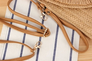 Detail of adjustable brown leather straps with gold metal clasps for straw bags