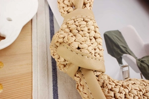 Detailed macro view of woven raffia texture with brown leather accents and white stitching