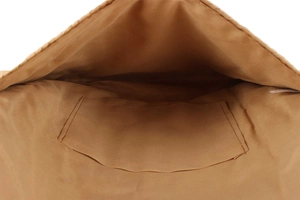 Close-up of the spacious interior lining and side pocket of the woven straw crossbody bag
