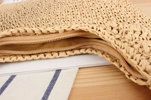Detailed macro view of woven straw bag featuring a smooth zipper and cotton lining