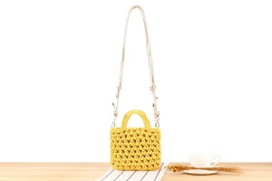 Macro detail of yellow handmade crochet woven bag with metal crossbody strap and mesh texture