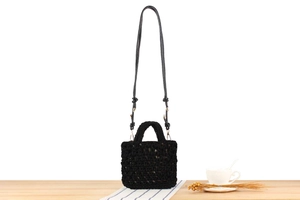 Detail of black handmade crochet mini bag with golden metal hooks on wooden table