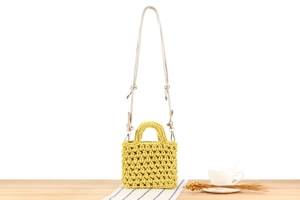 Close-up of yellow handmade crochet mini bag with woven texture and metal strap