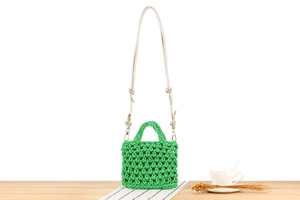 Detail of green handmade woven crochet bag with gold chain strap and knot detail