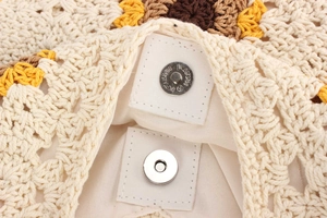 Detailed close-up of magnetic buckle and fabric lining on sunflower crochet bag
