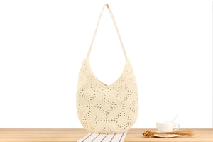 Dettaglio borsa a tracolla beige all'uncinetto con motivo floreale su legno