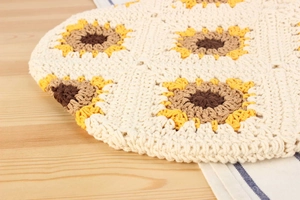 Close-up of handmade cotton crochet bag featuring detailed sunflower patterns and knit texture
