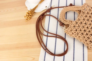 Detail of handmade woven cotton rope bag with hollow crochet texture and leather strap