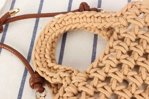 Close-up of handmade cotton rope weave with brown leather handle and gold hardware