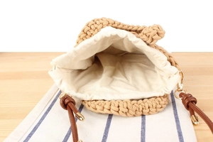 Detail of hand-woven cotton rope bag featuring a drawstring liner and leather strap