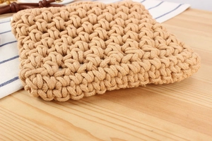 Close-up of handmade woven cotton rope bag showing detailed hollow crochet texture on wood table