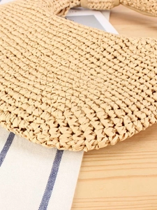 Straw shoulder bag with tight honeycomb texture on a wooden table for beach vacation