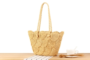 Detail of hand-woven straw tote bag with circular pattern and braided shoulder straps