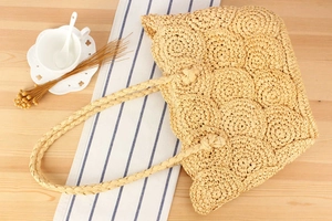 Detailed close-up of handmade woven straw bag with circular layered patterns on wooden surface