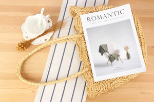Top-down view of woven straw tote bag on a rustic table with coffee and dried flowers