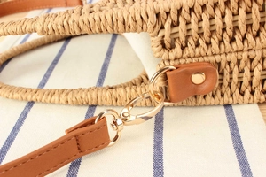 Dettaglio della borsa in paglia intrecciata con tracolla in pelle e fibbia dorata