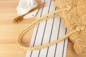 Close-up of thick twisted handle on a handmade woven straw handbag for summer