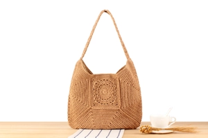 Detail of tan handmade crochet tote bag featuring intricate granny square woven patterns