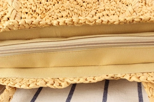 Detail of woven straw bag showing the resin zipper closure and soft fabric lining