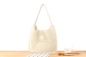 Detailed close-up of beige crochet shoulder bag with bohemian circular hollow knit texture