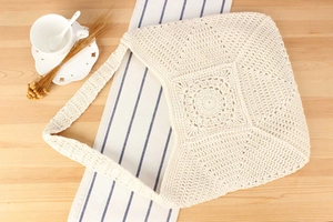 Macro detail of the white crochet tote bag showing intricate cotton stitching and floral patterns