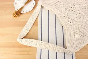 Detailed close-up of handmade cream crochet shoulder bag with hollow knit patterns