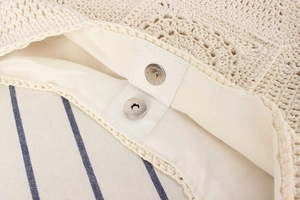 Detailed macro view of silver magnetic buckle and white lining in woven beach bag